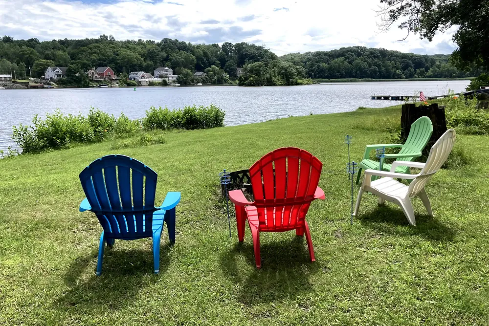 Adirondack chairs on the lawn above the river at Cabin 8